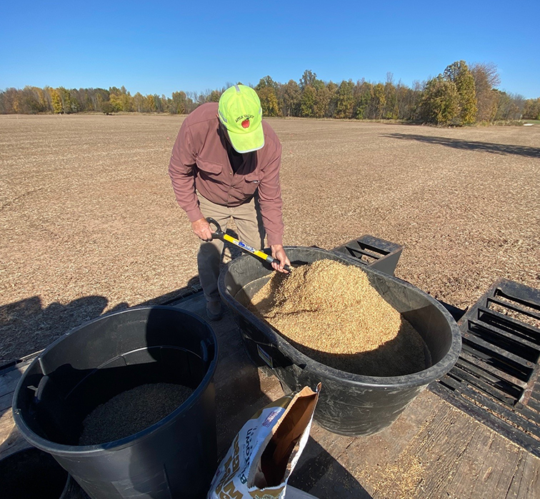 A volunteer seeds AriensCo's conservation property.